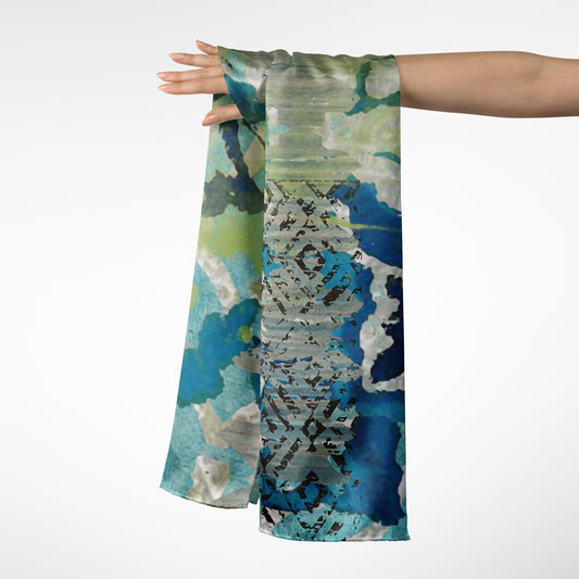 Scarf with a blue and green abstract pattern held by a person on a white background