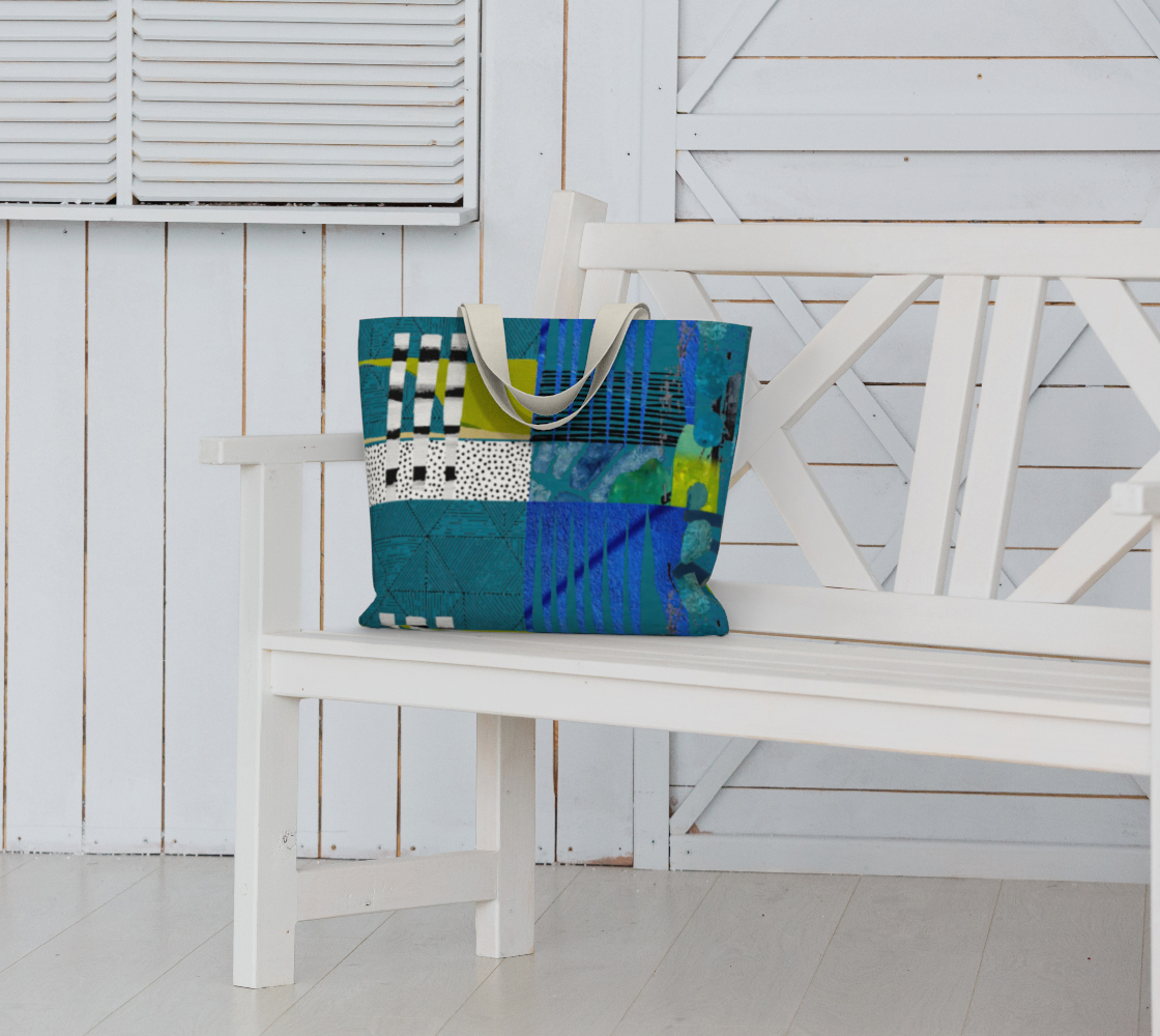 Blue tote bag with abstract patterns on a white bench against a white wooden wall.