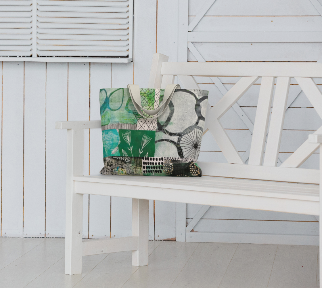 Tote bag with green and black pattern on a white bench against a white wooden wall.