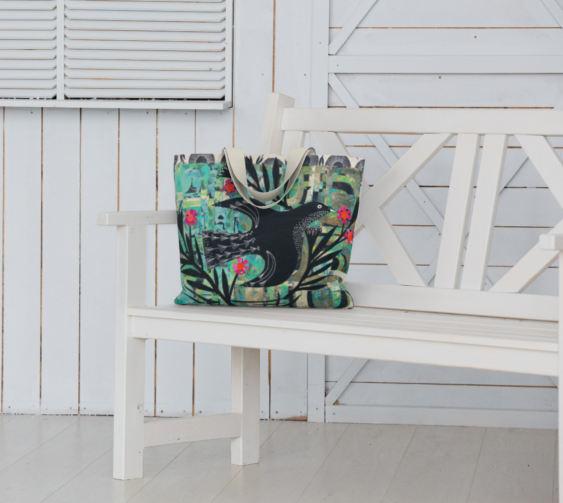 Colorful tote bag with a black bird design on a white bench against a white wooden wall.
