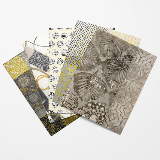 A fan arrangement of five patterned art collage papers  featuring abstract botanical and geometric designs in gray, gold, black, and white on a light gray background.