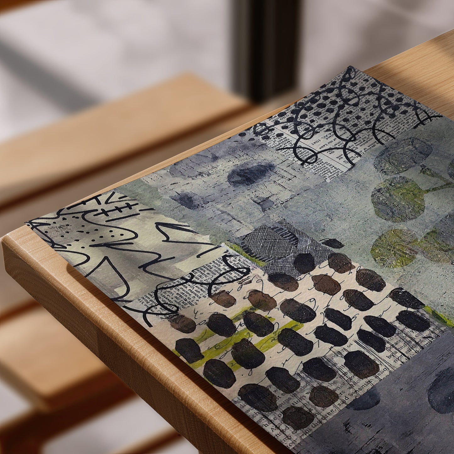 Abstract mixed-media art print featuring blue, gray, black, and olive green patterns, displayed on a light wood frame..