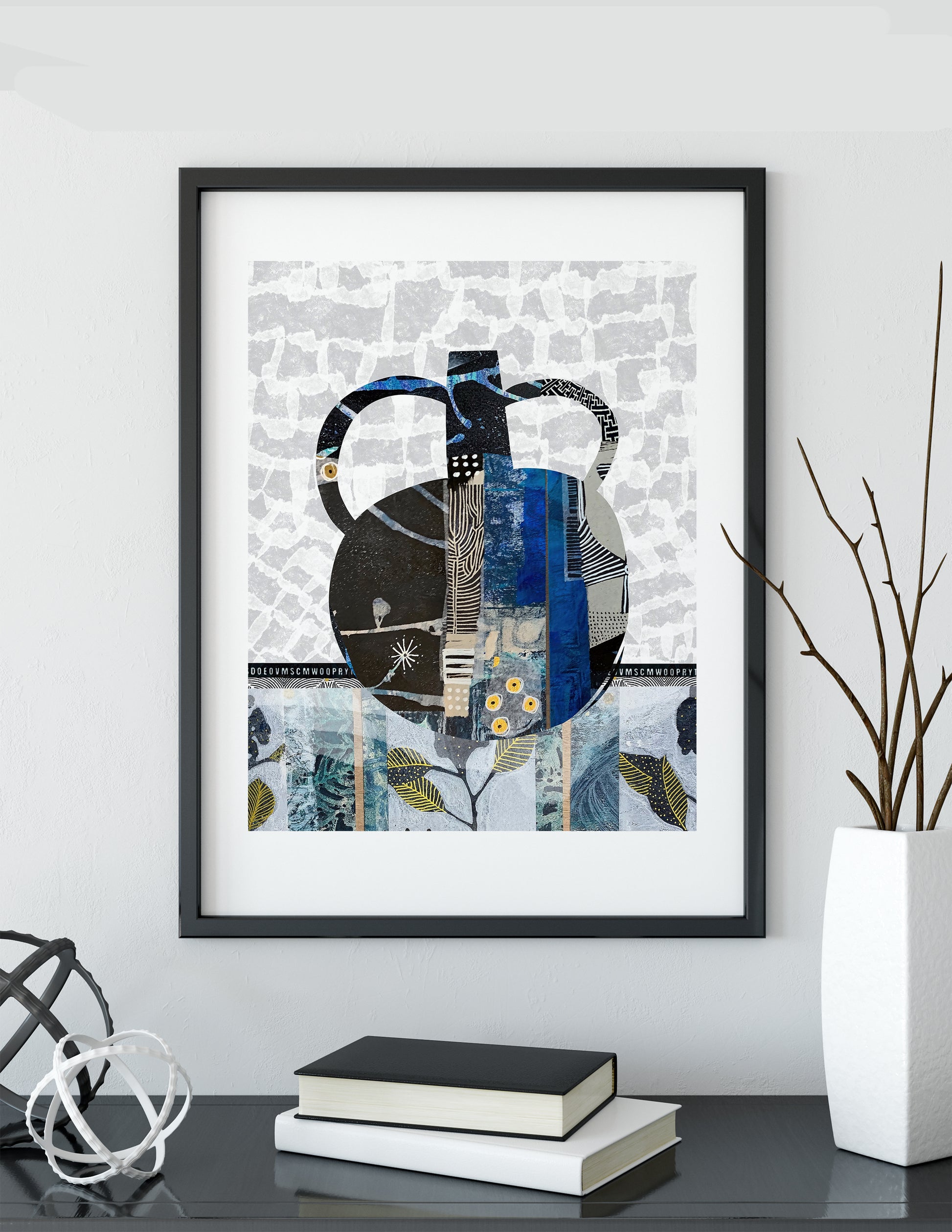 A framed abstract art print featuring a stylized teapot in shades of blue, black, and white, displayed on a shelf next to books and a vase with branches.