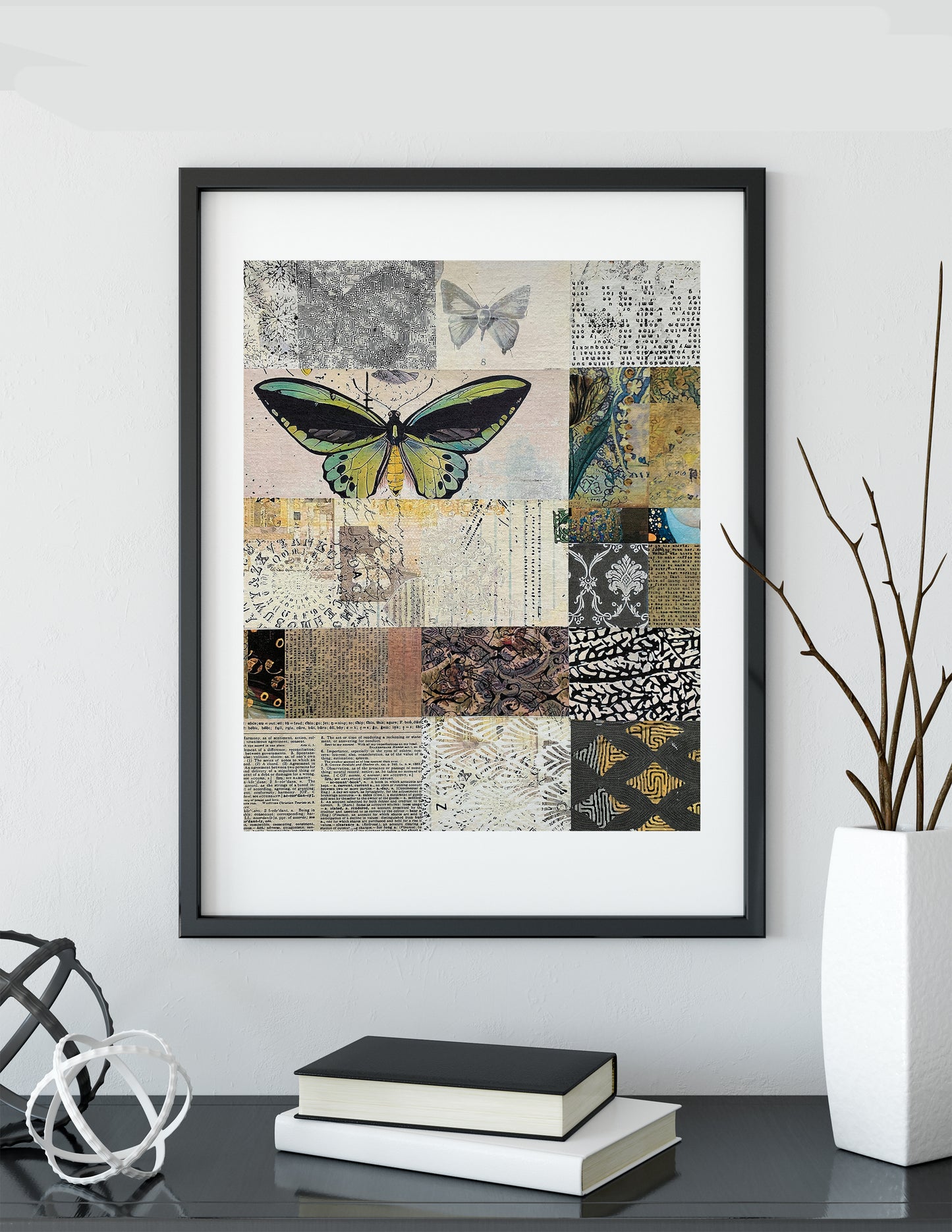 Framed wall art featuring a butterfly over a patchwork collage of vintage-style patterns and textures, displayed on a shelf above books and a vase.