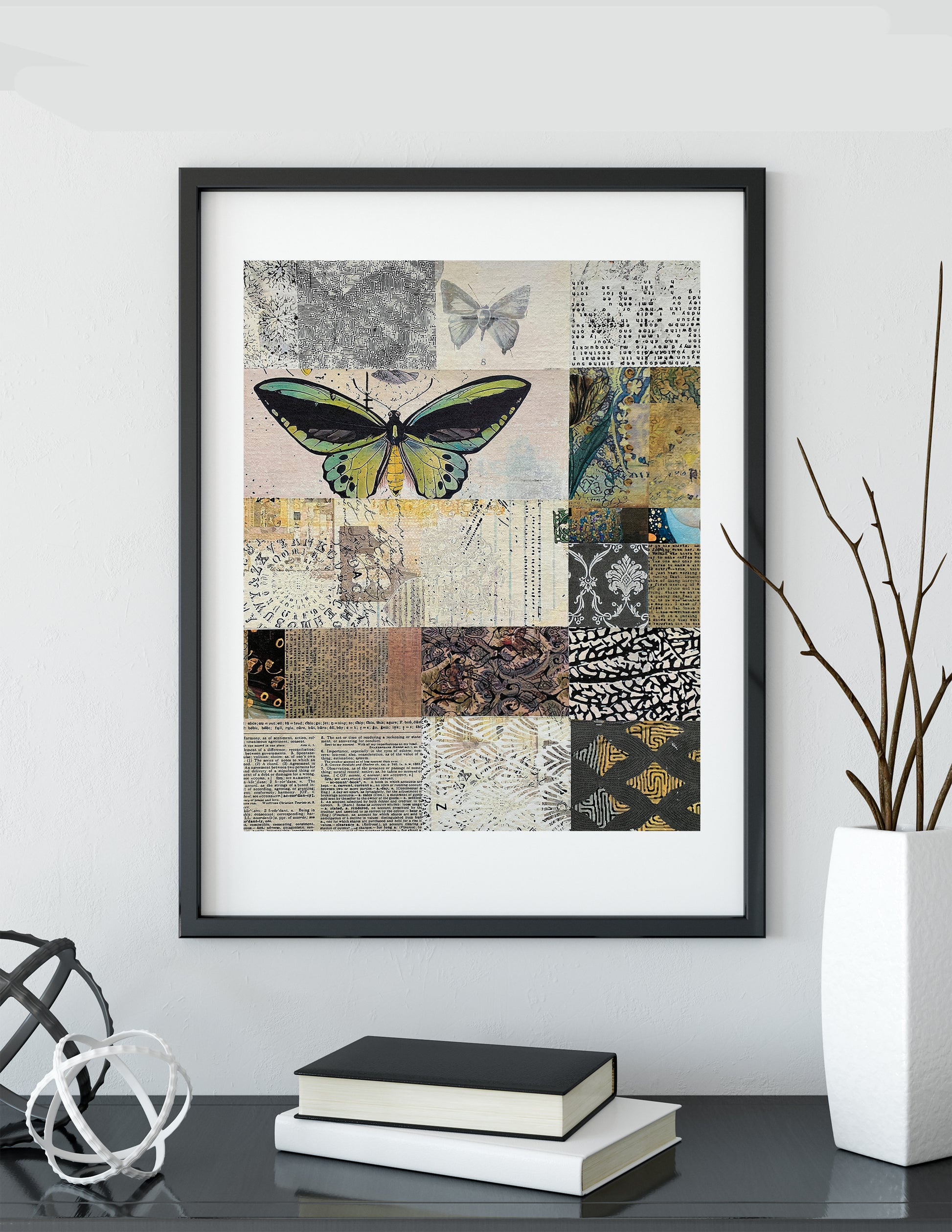 Framed wall art featuring a butterfly over a patchwork collage of vintage-style patterns and textures, displayed on a shelf above books and a vase.
