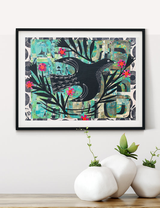 Framed wall art featuring a black bird silhouette over a collage-style background of teal, green, gray, and cream shapes, with small pink flower accents. 