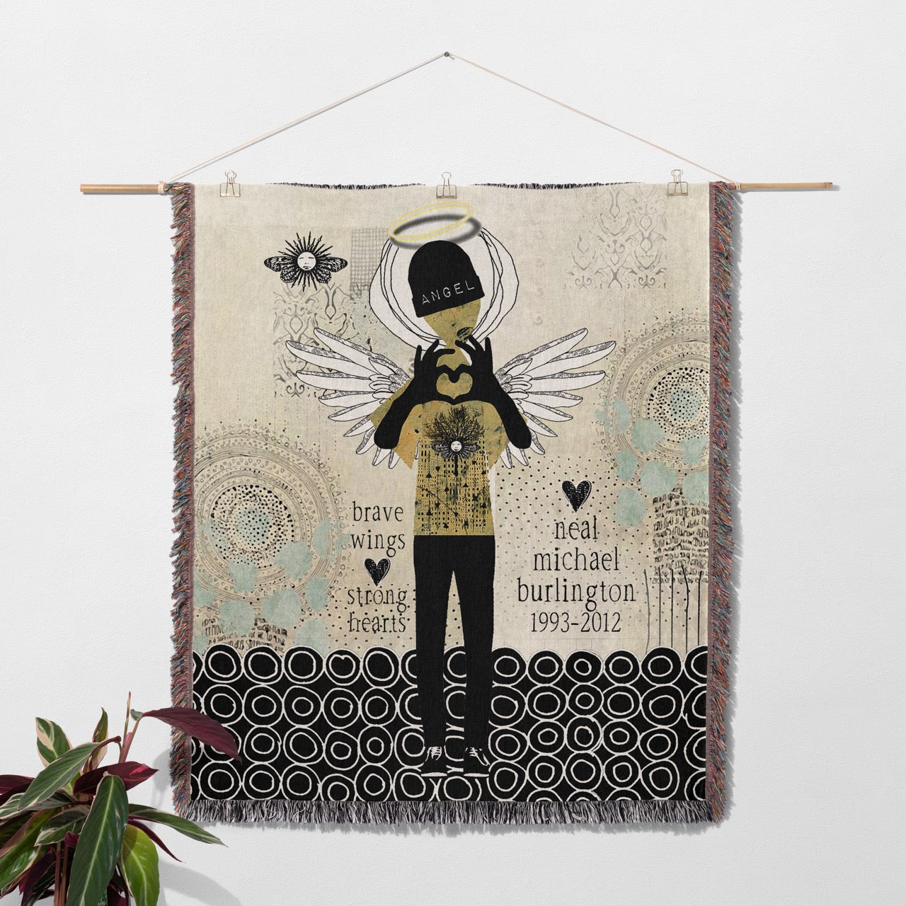 Woven tapestry with angel design and text on a white wall