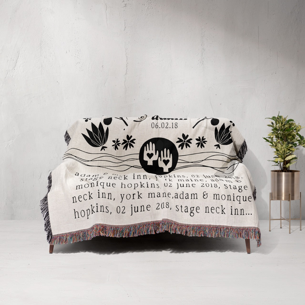 Decorative throw blanket with text and design on a couch against a white wall.