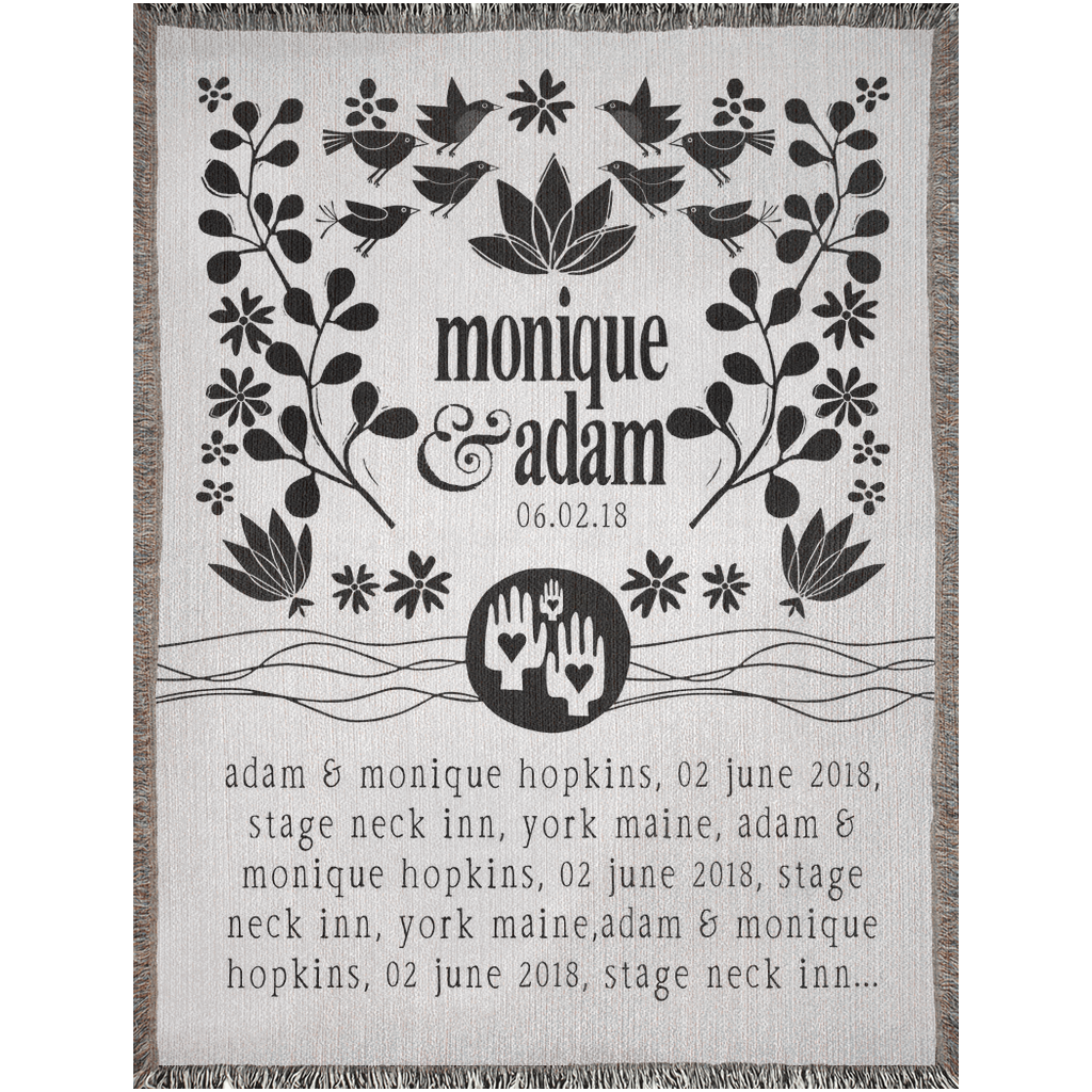 Decorative blanket with black floral and bird patterns, text, and a logo on a white background.