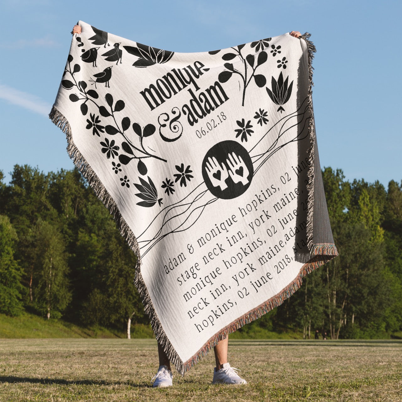 Person holding a personalized blanket with decorative text and designs outdoors.