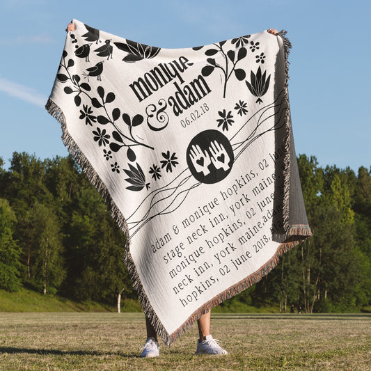 Person holding a personalized blanket with decorative text and designs outdoors.
