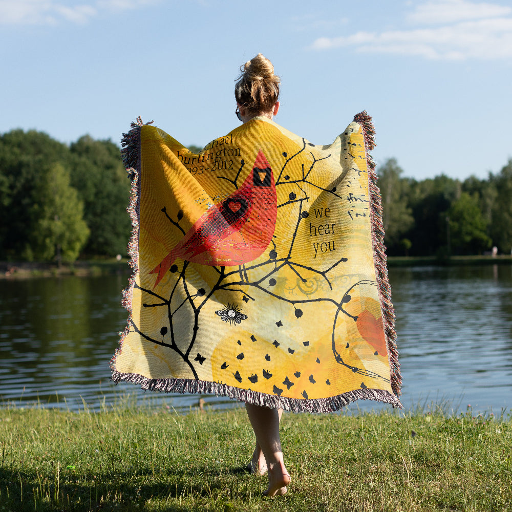 Person standing by a lake with a yellow blanket featuring a red cardinal design.