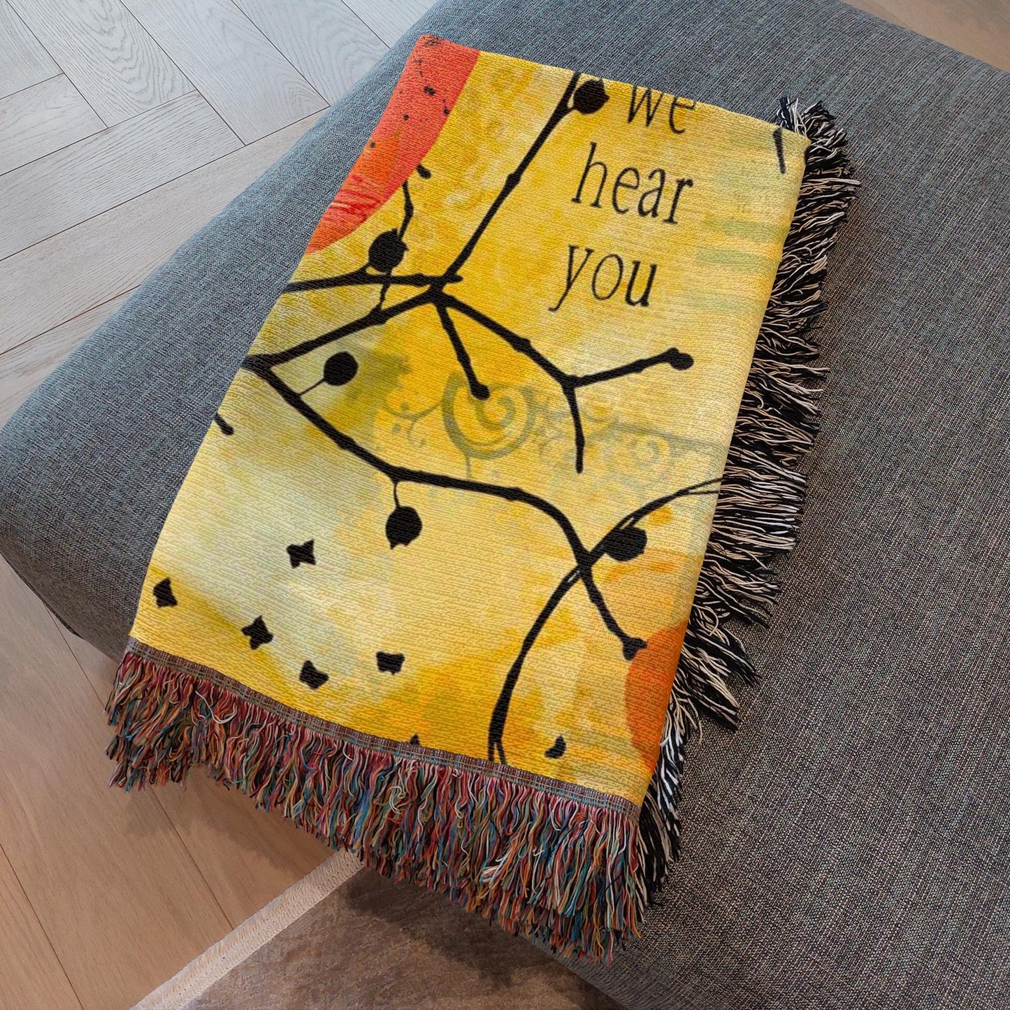 Decorative blanket with 'We hear you' text on a gray surface