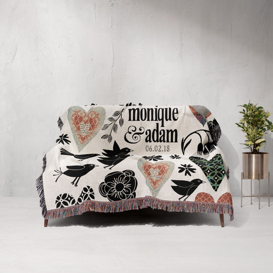 Decorative blanket with artistic designs and text on a white couch against a light gray wall.