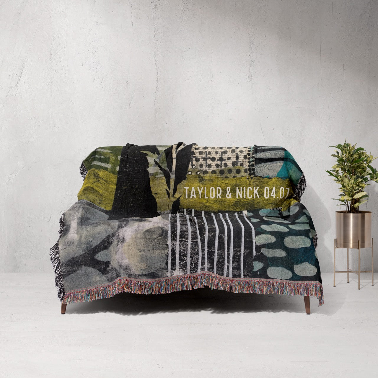 Textile with patterns and text draped over a sofa against a white wall.