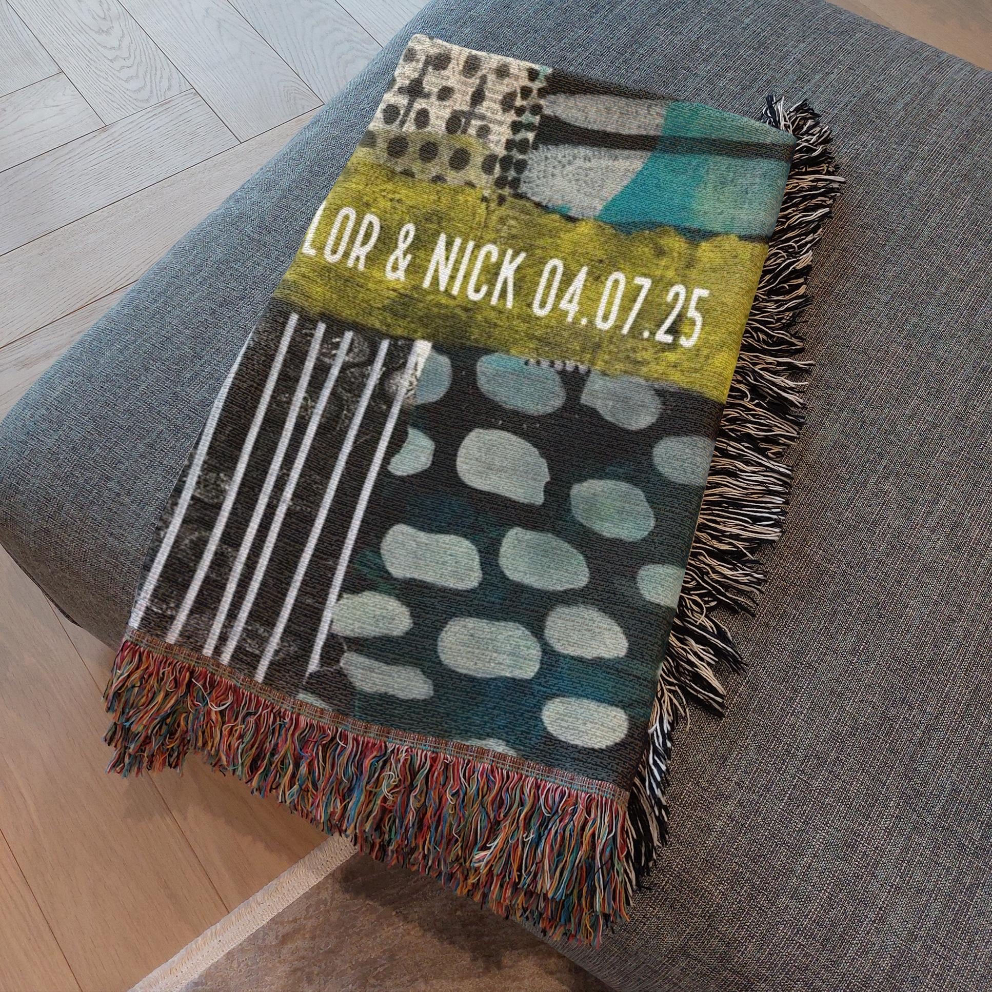 Personalized throw blanket with text and abstract patterns on a gray surface.