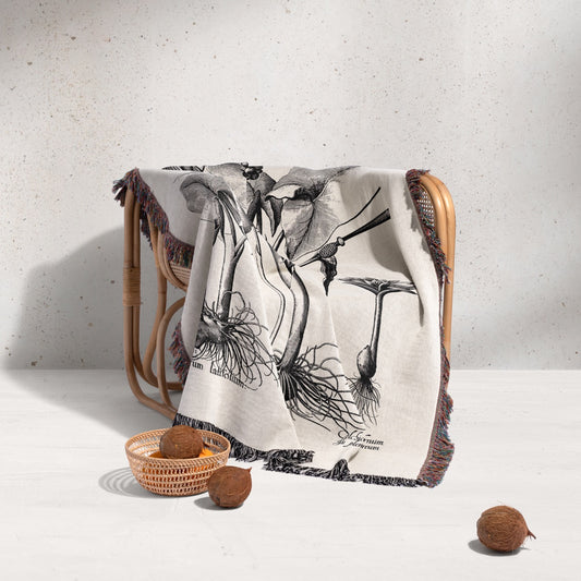Decorative blanket with nature-themed design draped over a chair on a light background